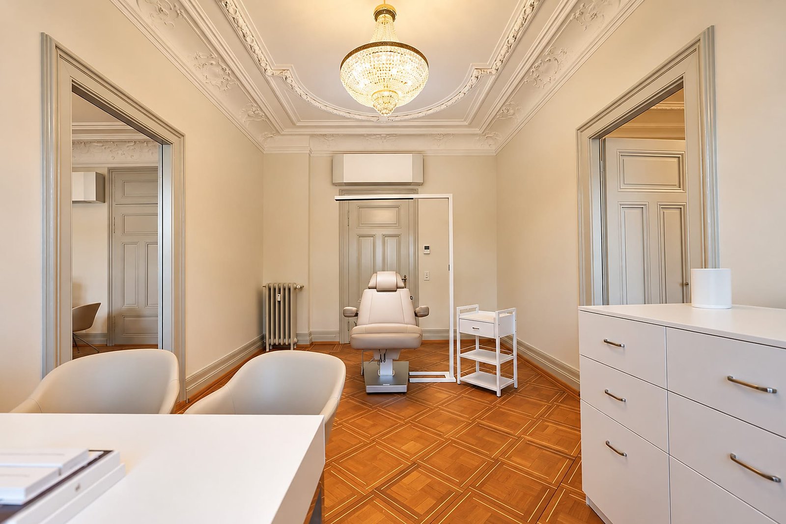 Behandlungsraum der Klinik mit Beratungstisch, Behandlungsstuhl und Stuckdecke